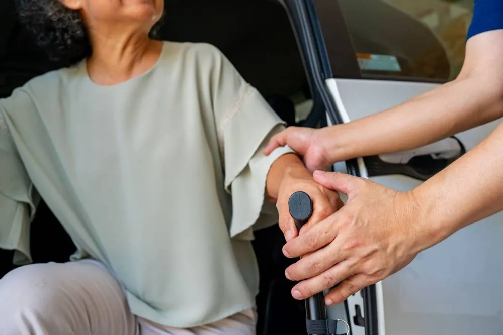 Driver helping a senior woman into a car